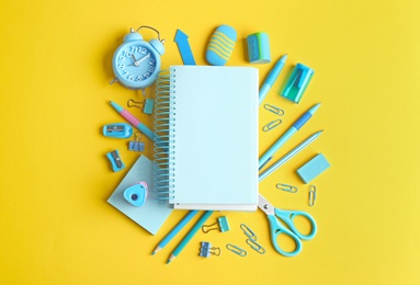 Photo of Different school stationery and blank notebook on yellow background, flat lay. Space for text