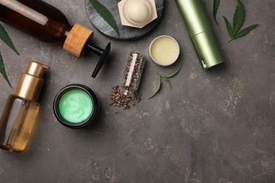 Photo of Hemp cosmetics and green leaves on grey table, flat lay. Space for text