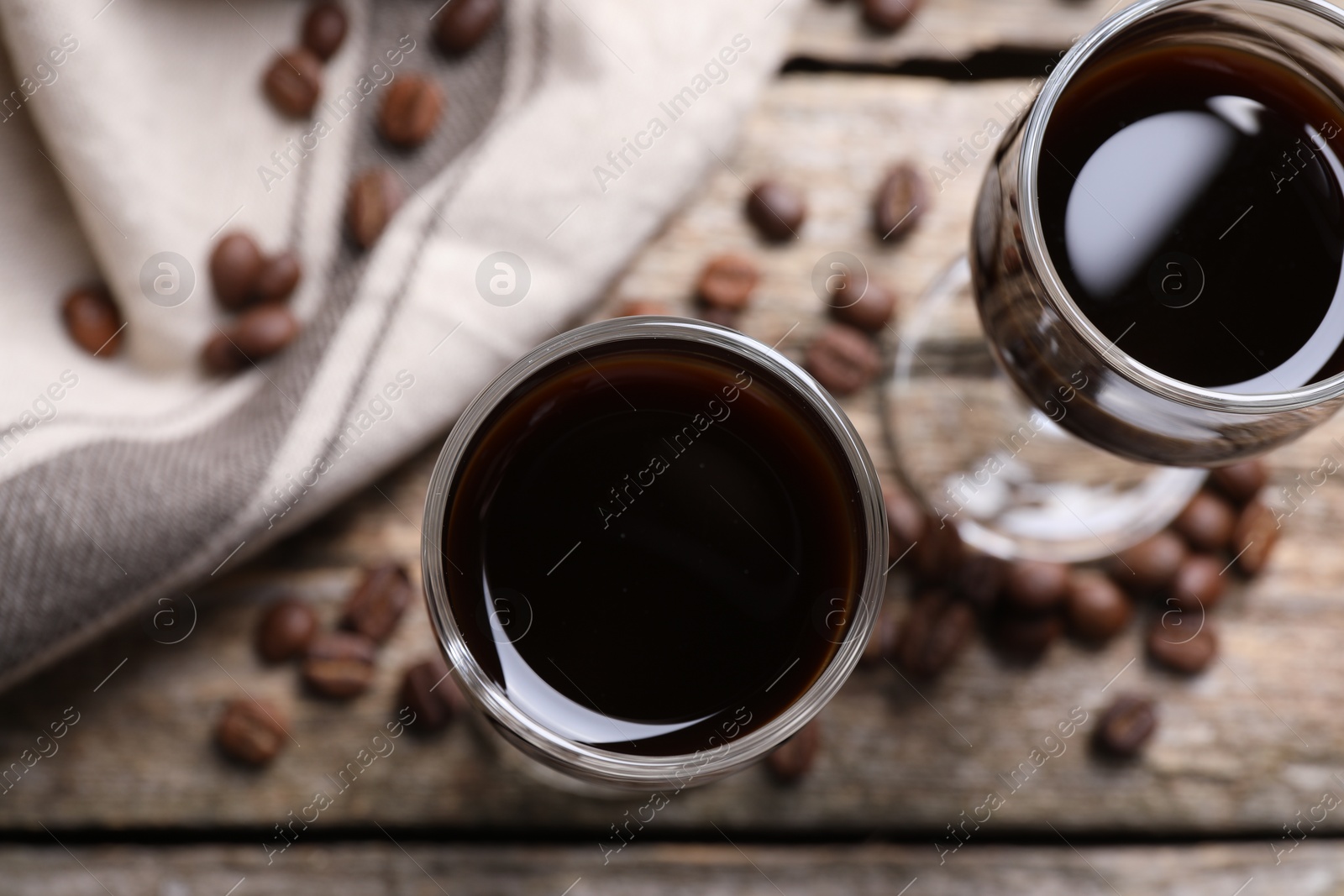 Photo of Glasses of coffee liqueur on wooden table, flat lay