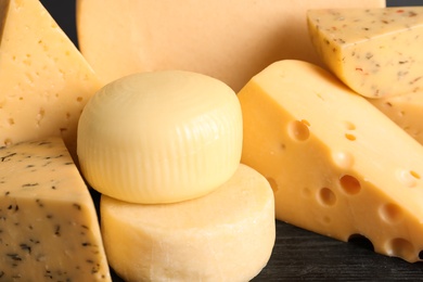 Photo of Different sorts of cheese on wooden table, closeup