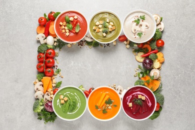 Various cream soups, ingredients and space for text on grey background, flat lay. Healthy food