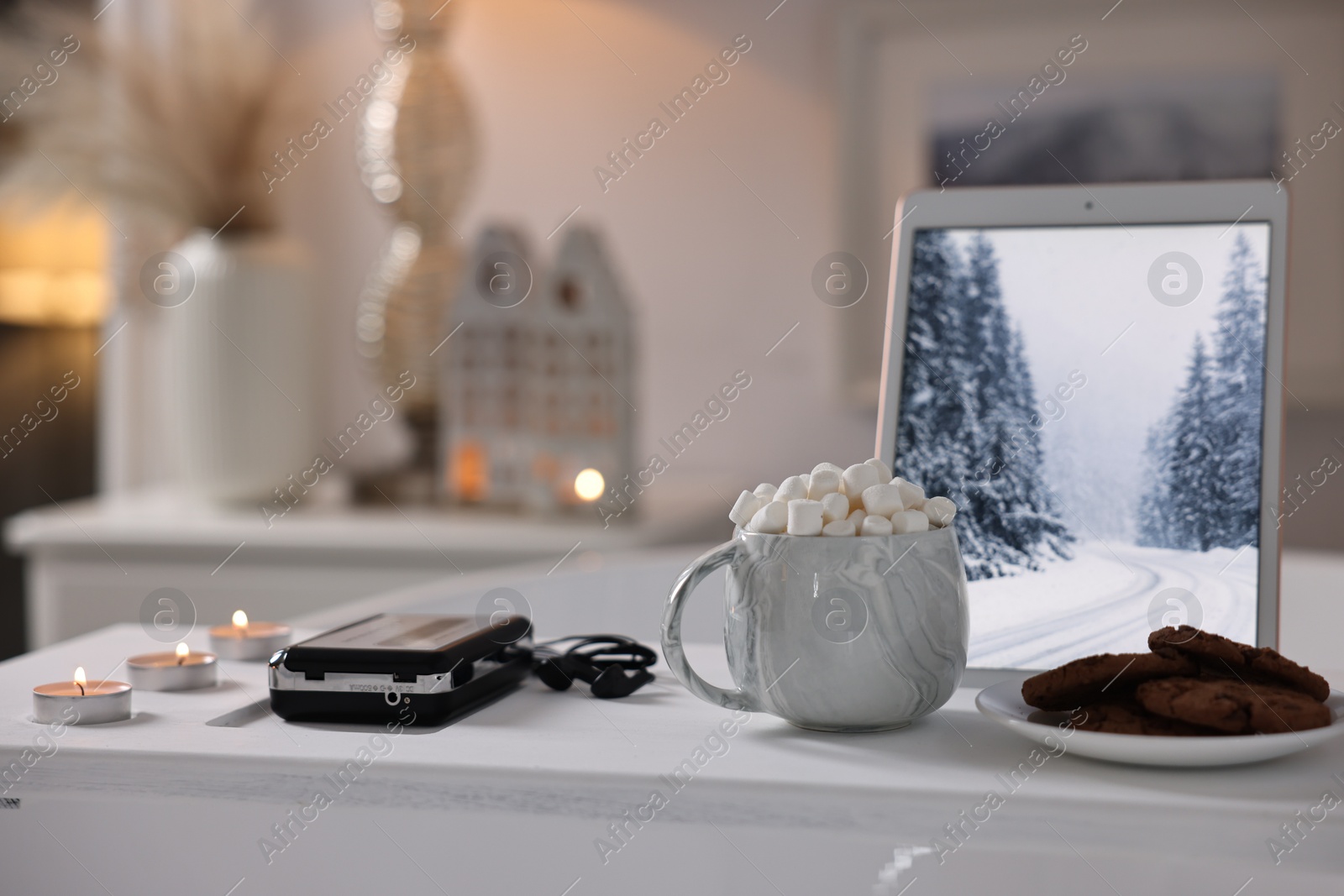 Photo of White wooden tray with tablet, cassette player, hot drink and burning candles on bathtub in bathroom