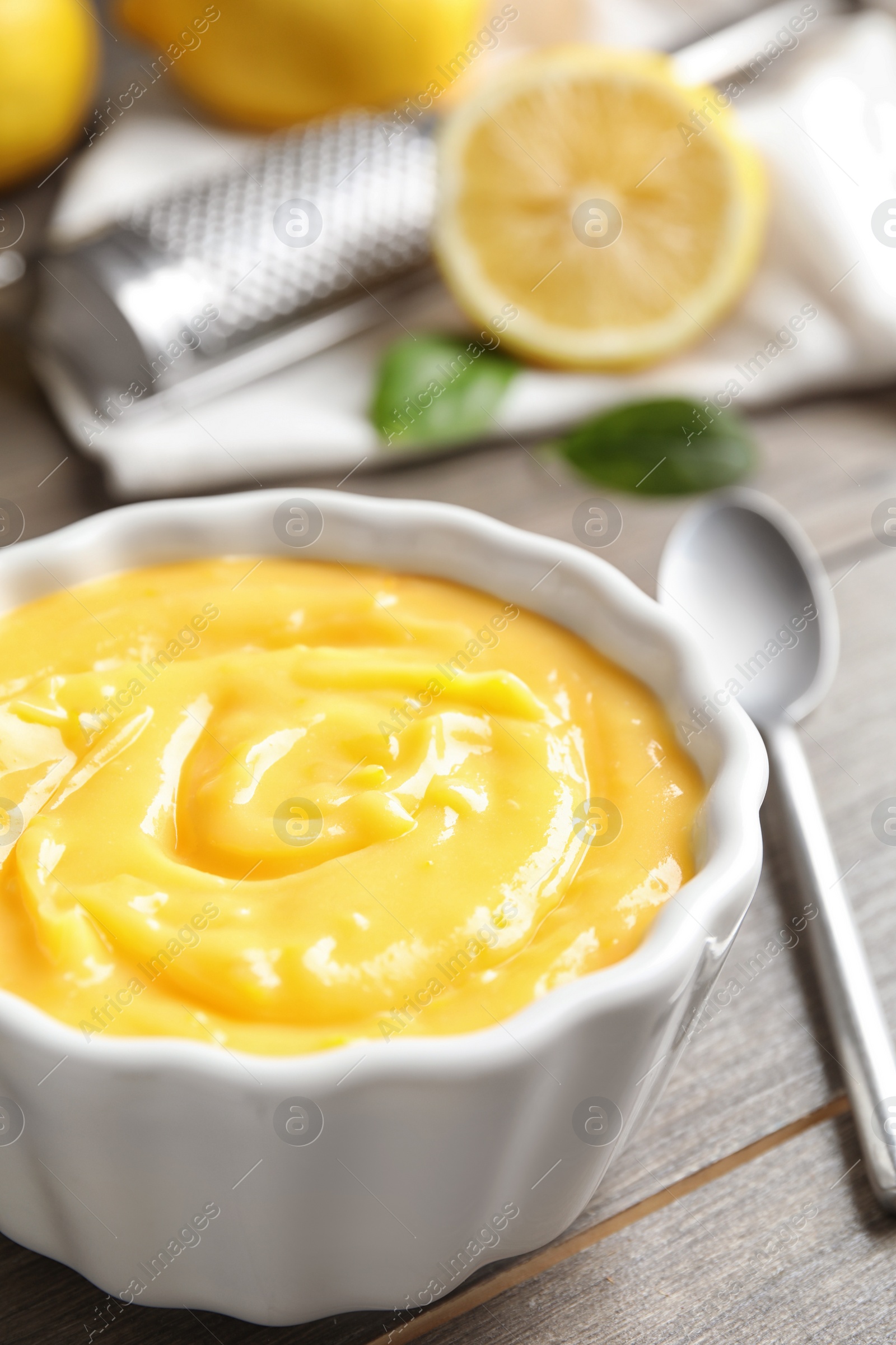 Photo of Delicious lemon curd in bowl on wooden table, closeup