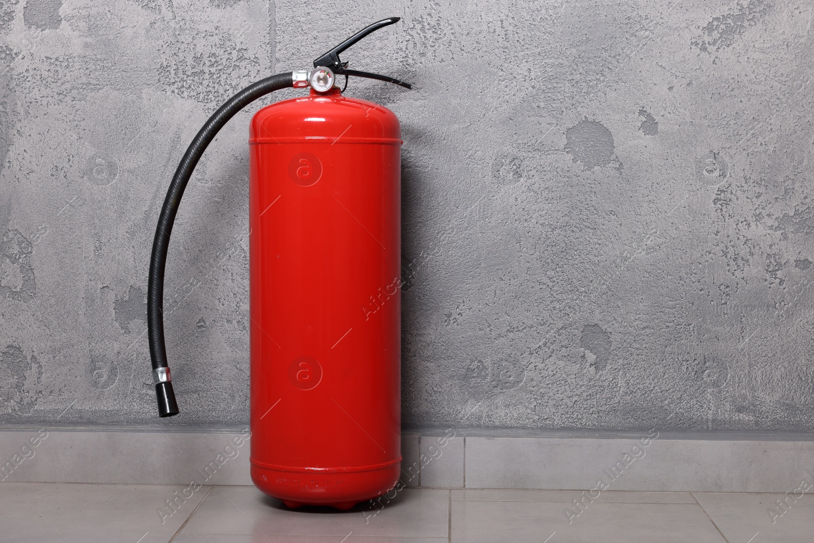 Photo of Red fire extinguisher near grey wall, space for text