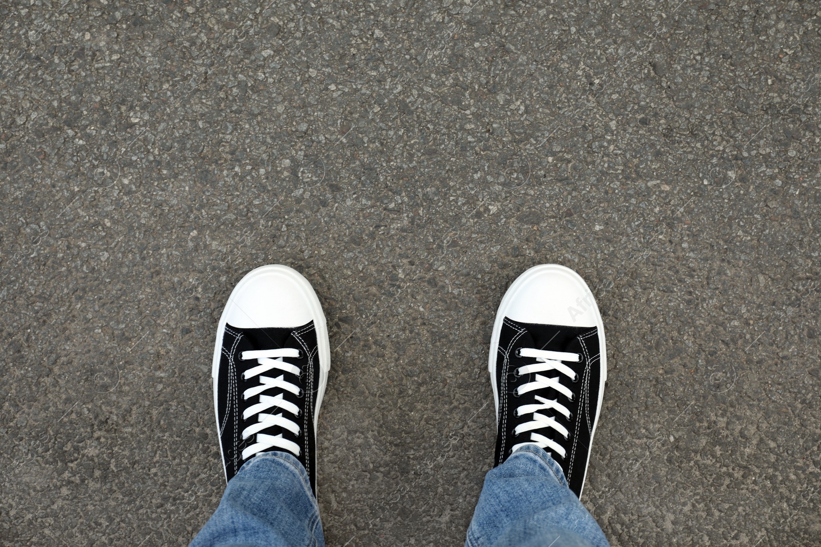 Photo of Man in sneakers standing on asphalt, top view. Space for text