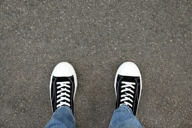 Photo of Man in sneakers standing on asphalt, top view. Space for text