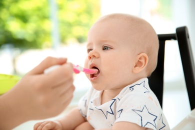 Photo of Mother feeding her cute little baby at home, closeup