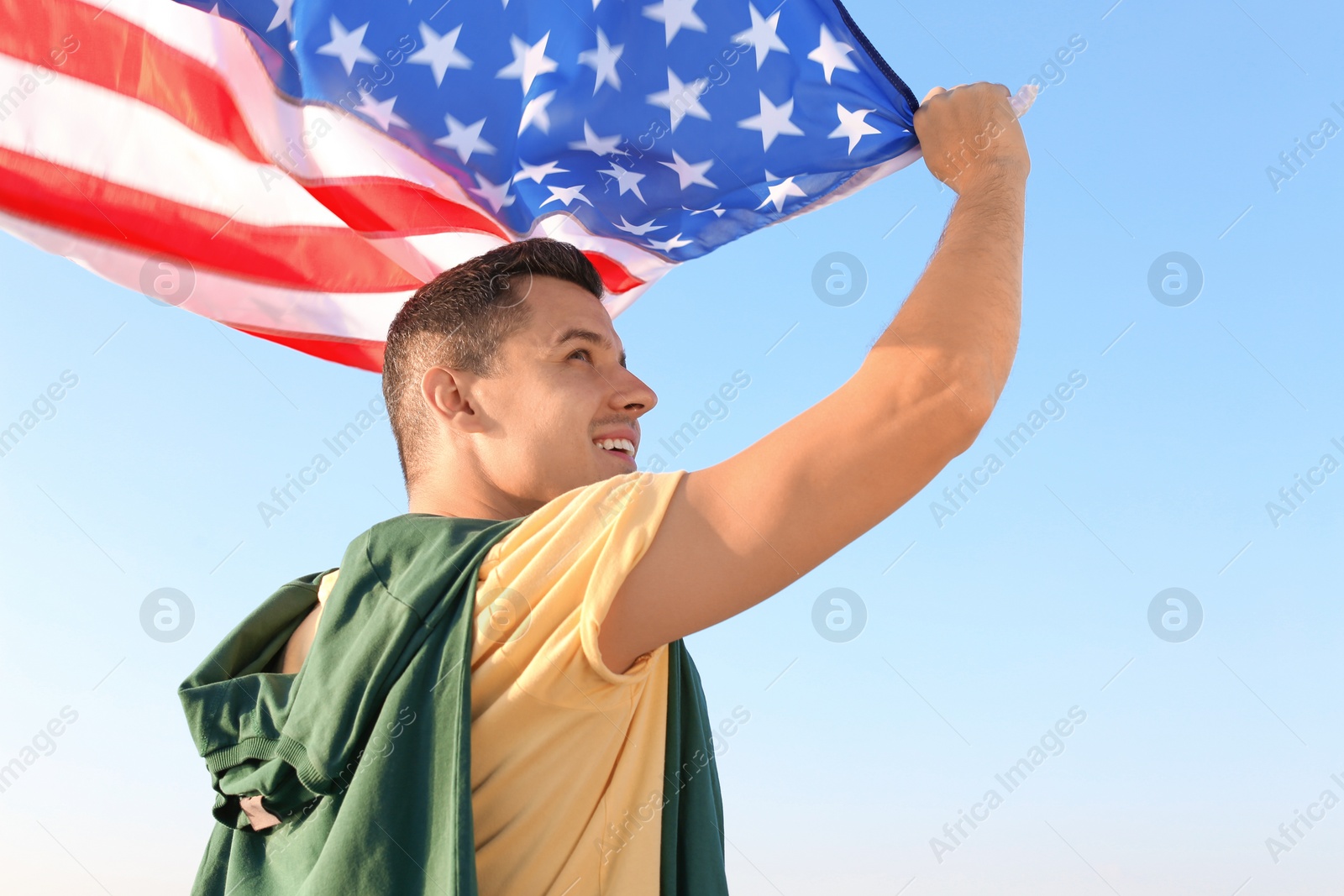 Photo of Man with American flag against blue sky