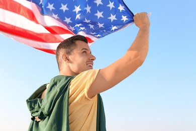 Photo of Man with American flag against blue sky