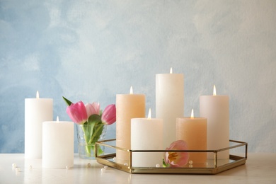 Photo of Composition with burning candles on table against color background