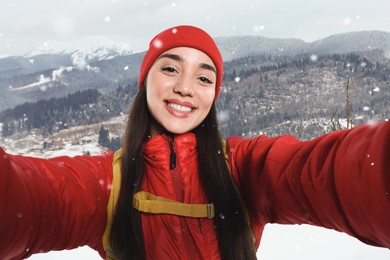 Image of Happy tourist with backpack taking selfie in snowy mountains