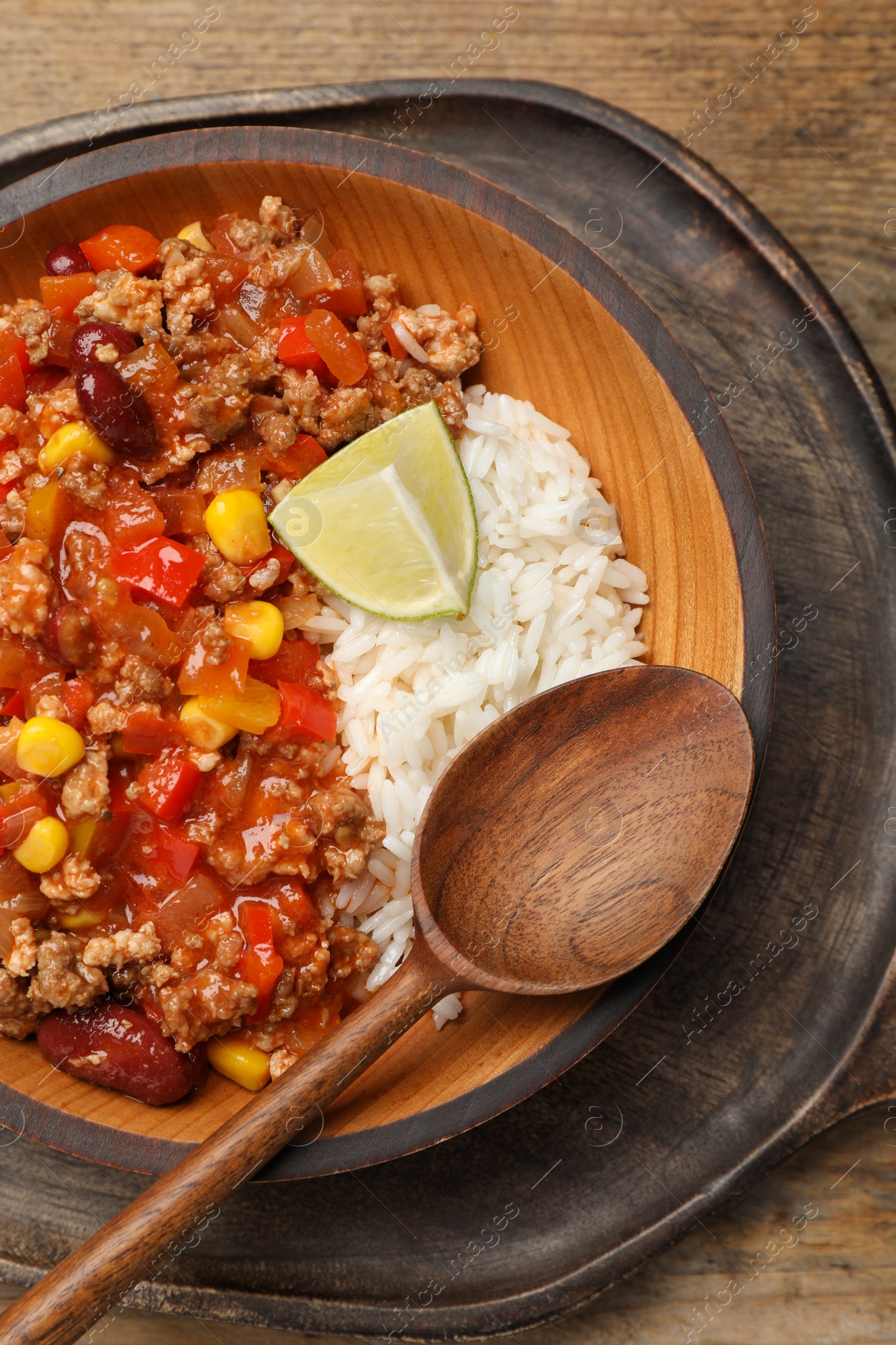 Photo of Plate of rice with chili con carne on wooden table, top view