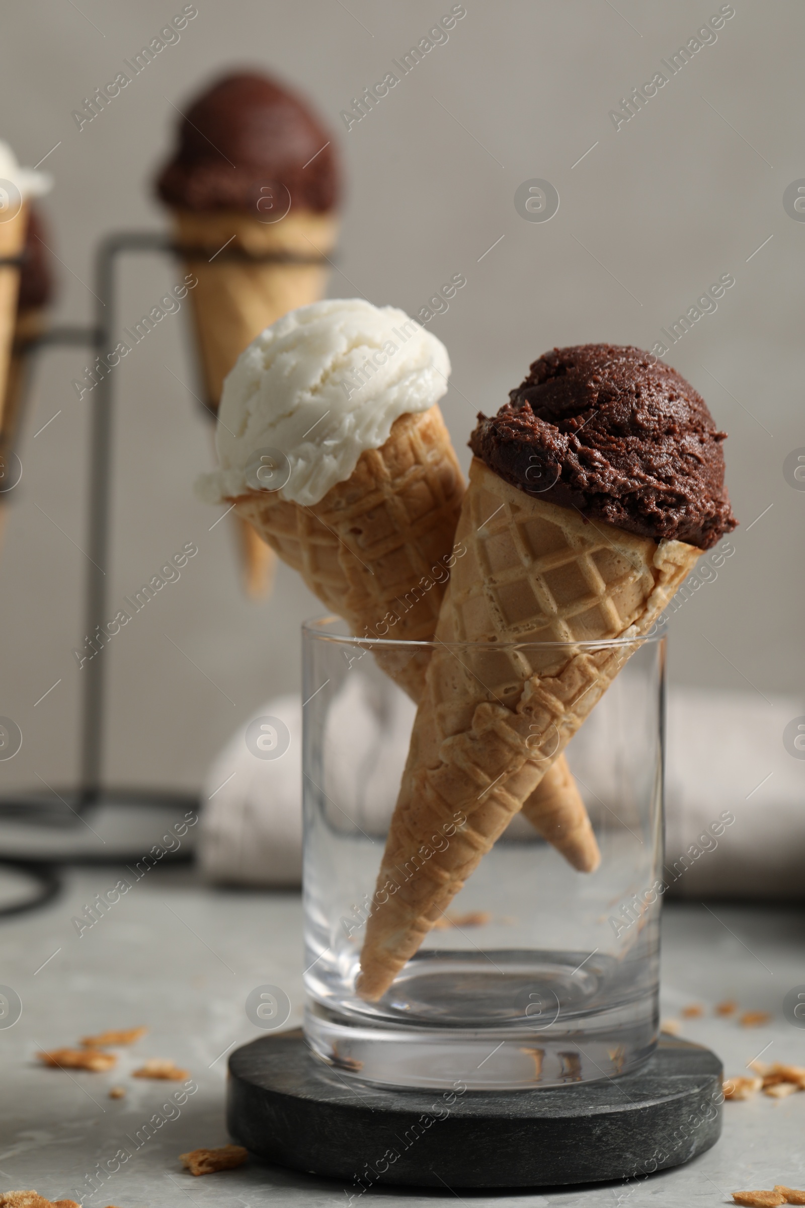 Photo of Tasty ice cream scoops in waffle cones on grey marble table, closeup