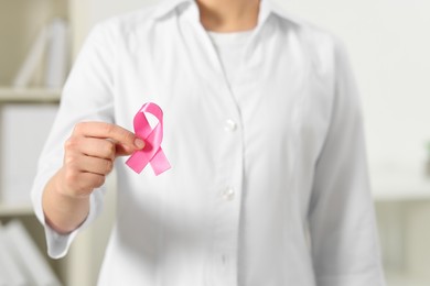 Photo of Mammologist with pink ribbon in hospital, closeup. Breast cancer awareness