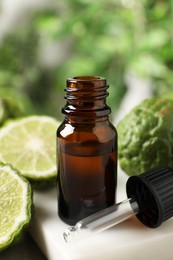 Photo of Glass bottle of bergamot essential oil and dropper on table