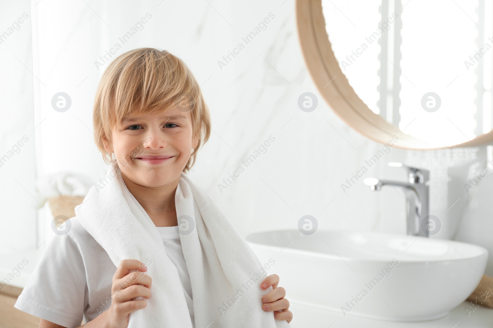 Photo of Cute little boy with towel in bathroom. Space for text