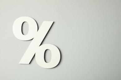 White percent sign on light grey background, top view. Space for text