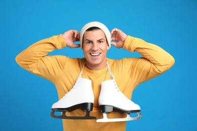 Photo of Emotional man with ice skates on light blue background