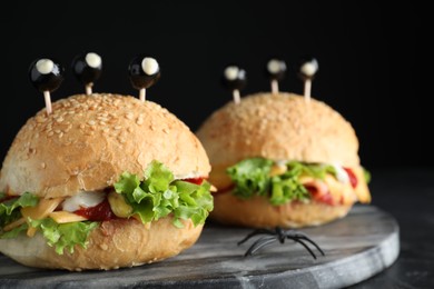 Photo of Cute monster burgers served on black table. Halloween party food