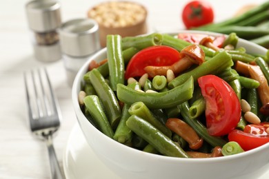 Photo of Delicious salad with green beans, mushrooms, pine nuts and tomatoes on white table, closeup