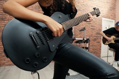 Photo of African American woman playing electric guitar during rehearsal in studio, closeup. Music band practice