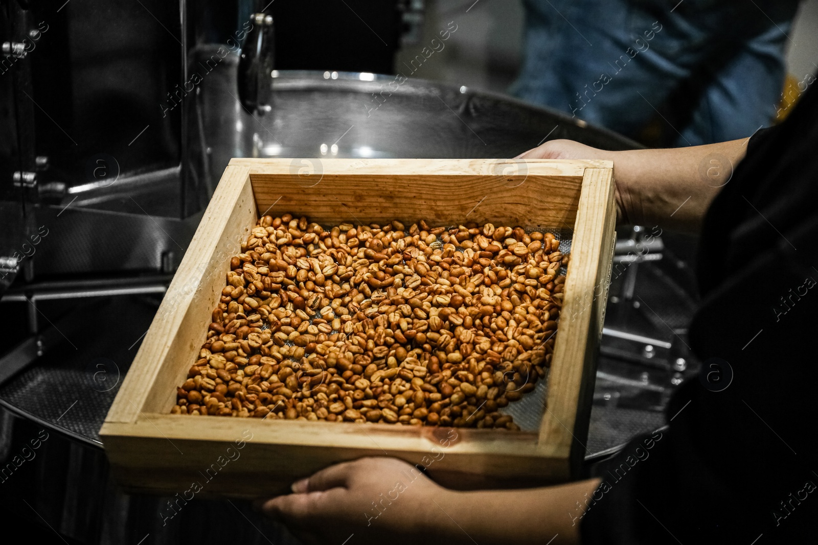 Photo of Man holding sieve with coffee beans indoors, closeup