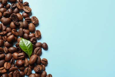 Photo of Fresh green coffee leaf and beans on color background, flat lay with space for text