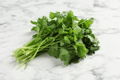 Photo of Bunch of fresh aromatic cilantro on white marble table