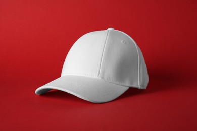 Photo of Stylish white baseball cap on red background