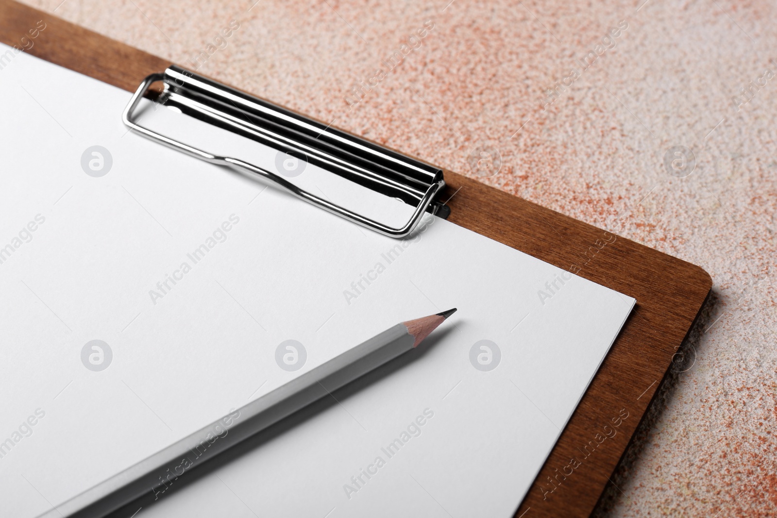 Photo of New clipboard with sheet of blank paper and pencil on color textured table, closeup