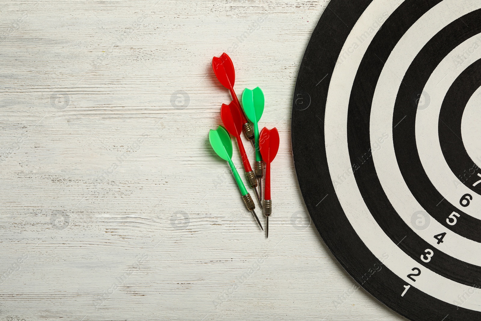 Photo of Dart board with color arrows on white wooden background, top view. Space for text