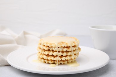 Photo of Tasty waffles with condensed milk on light grey table