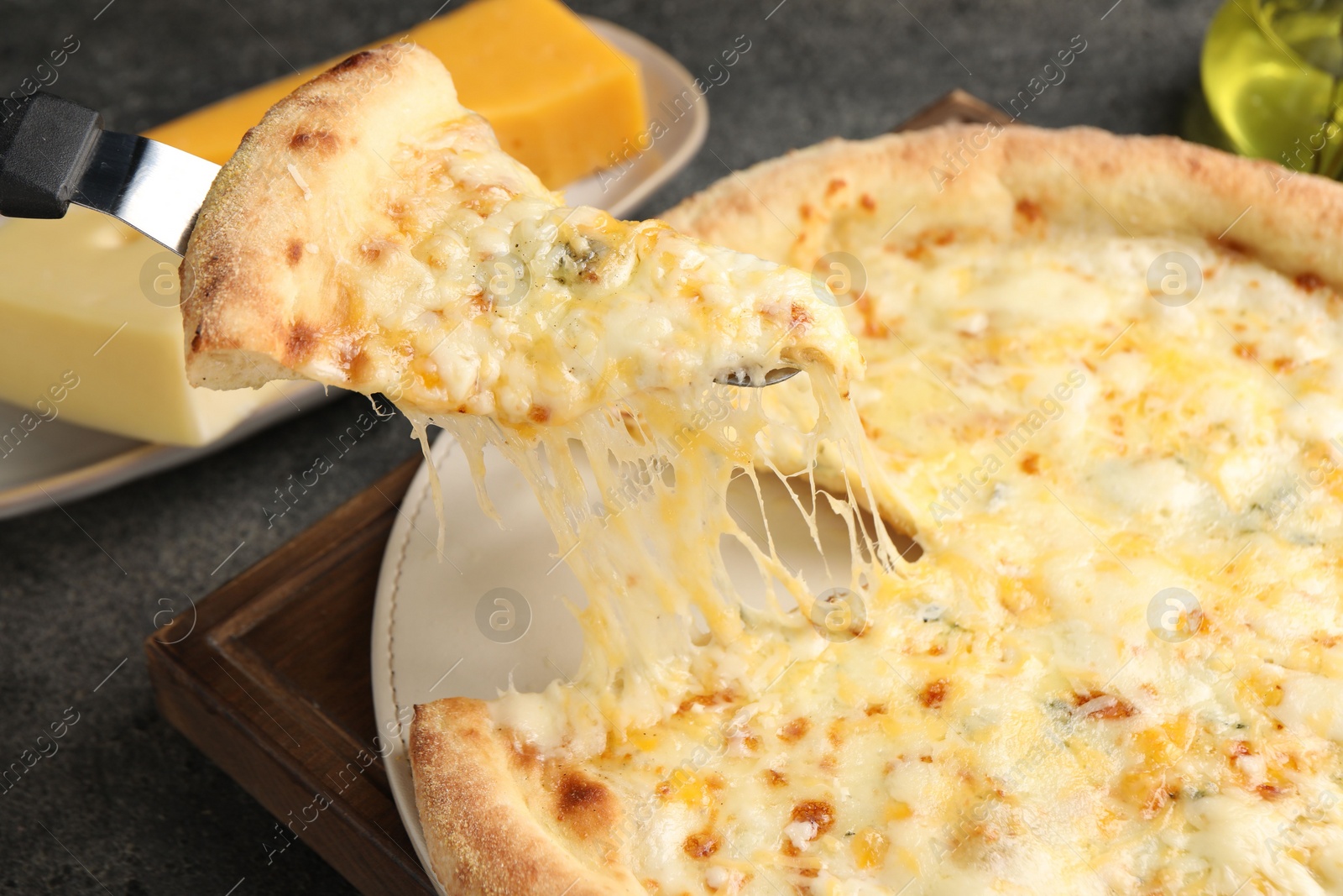 Photo of Taking piece of delicious cheese pizza at grey table, closeup