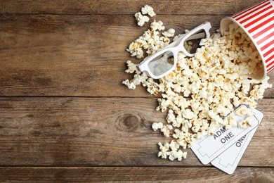 Popcorn, cinema tickets and 3d glasses  on wooden background, flat lay. Space for text