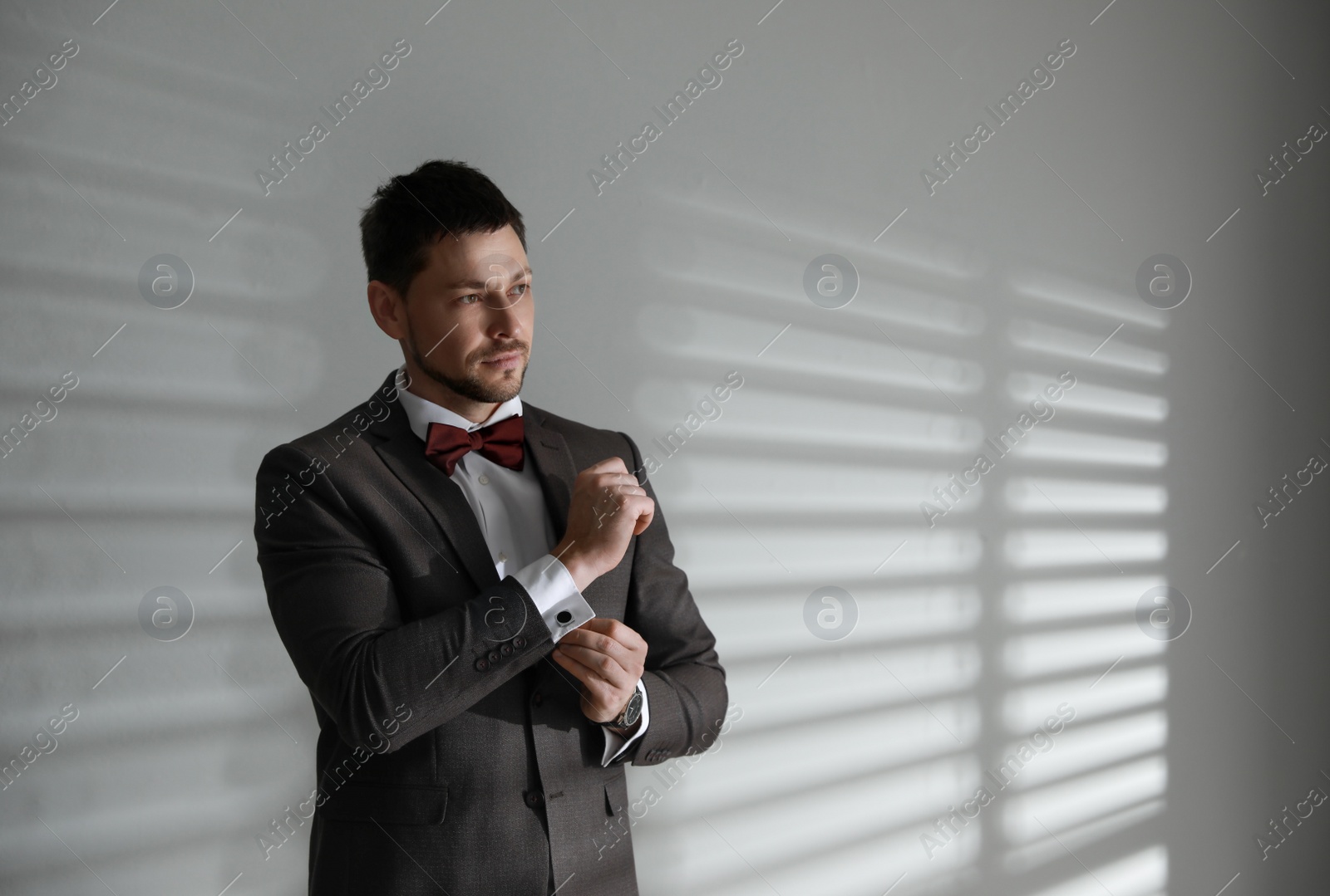 Photo of Man wearing stylish suit and cufflinks near white wall, space for text