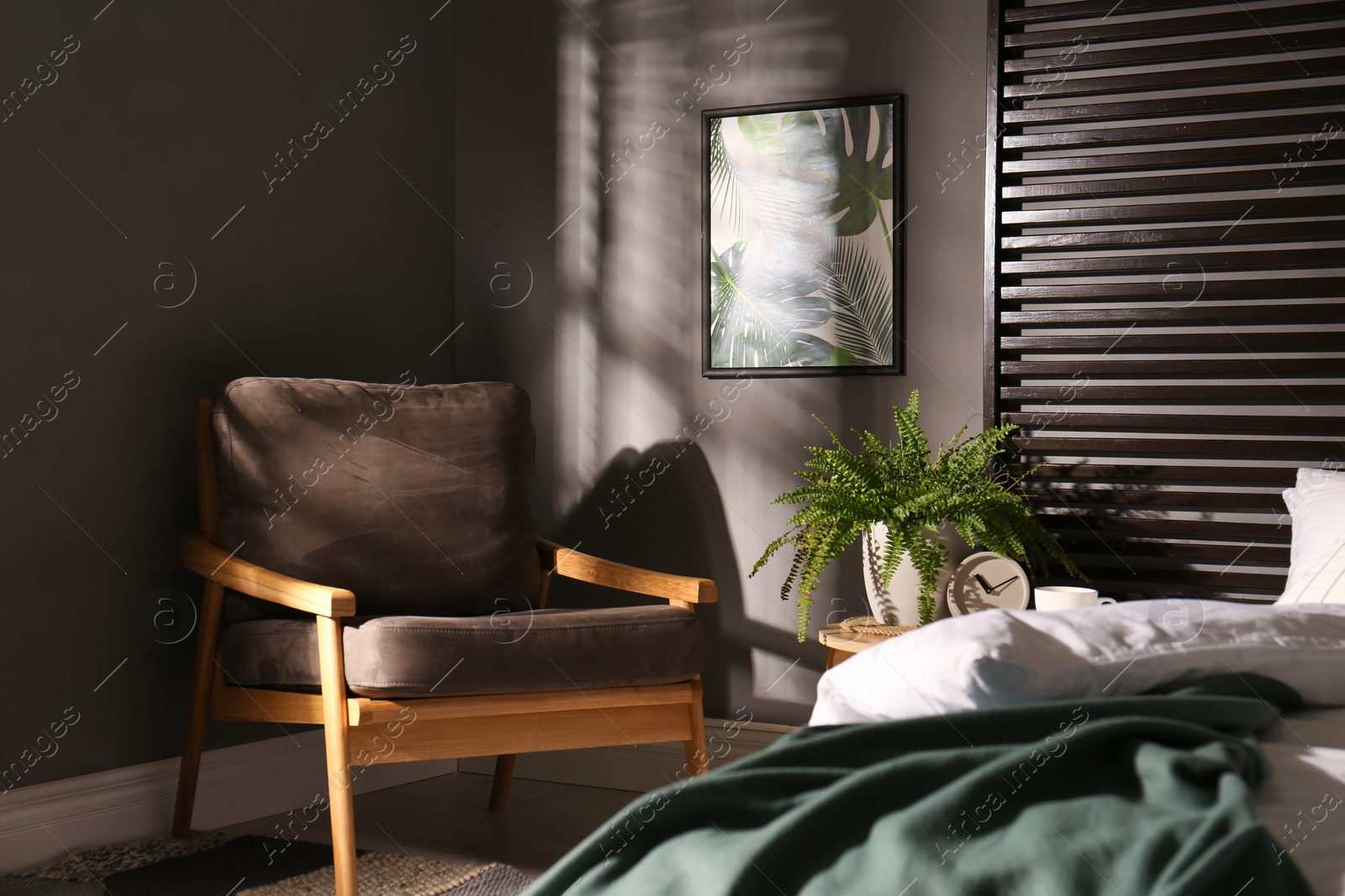 Photo of Comfortable bedroom with armchair and picture on wall. Interior design