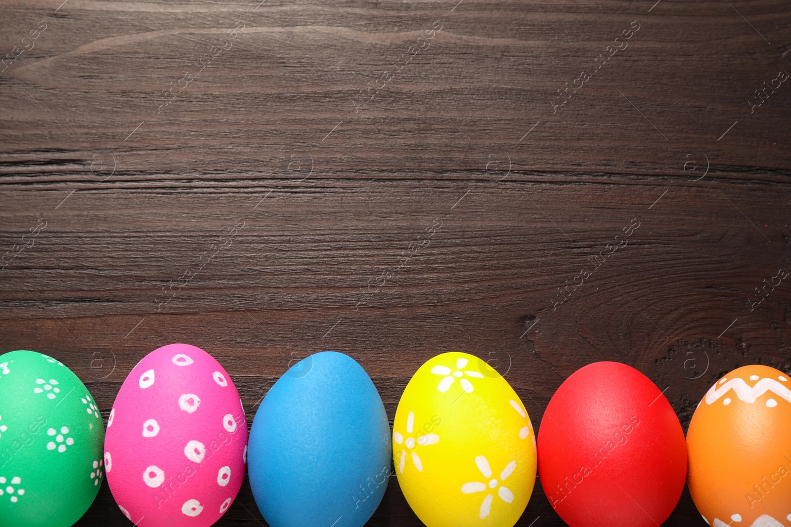 Photo of Colorful Easter eggs on wooden background, flat lay. Space for text