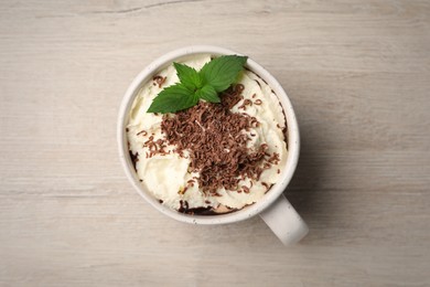 Photo of Cup of delicious hot chocolate with whipped cream and mint on white wooden table, top view