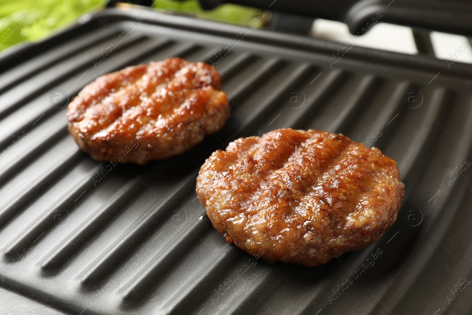 Photo of Delicious hamburger patties on electric grill, closeup