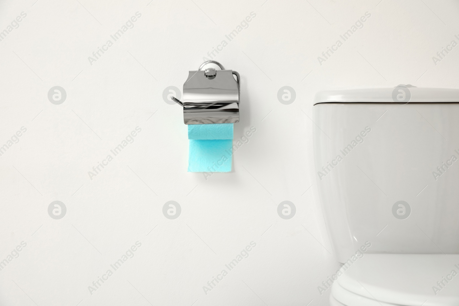 Photo of Holder with toilet paper roll on white wall in bathroom