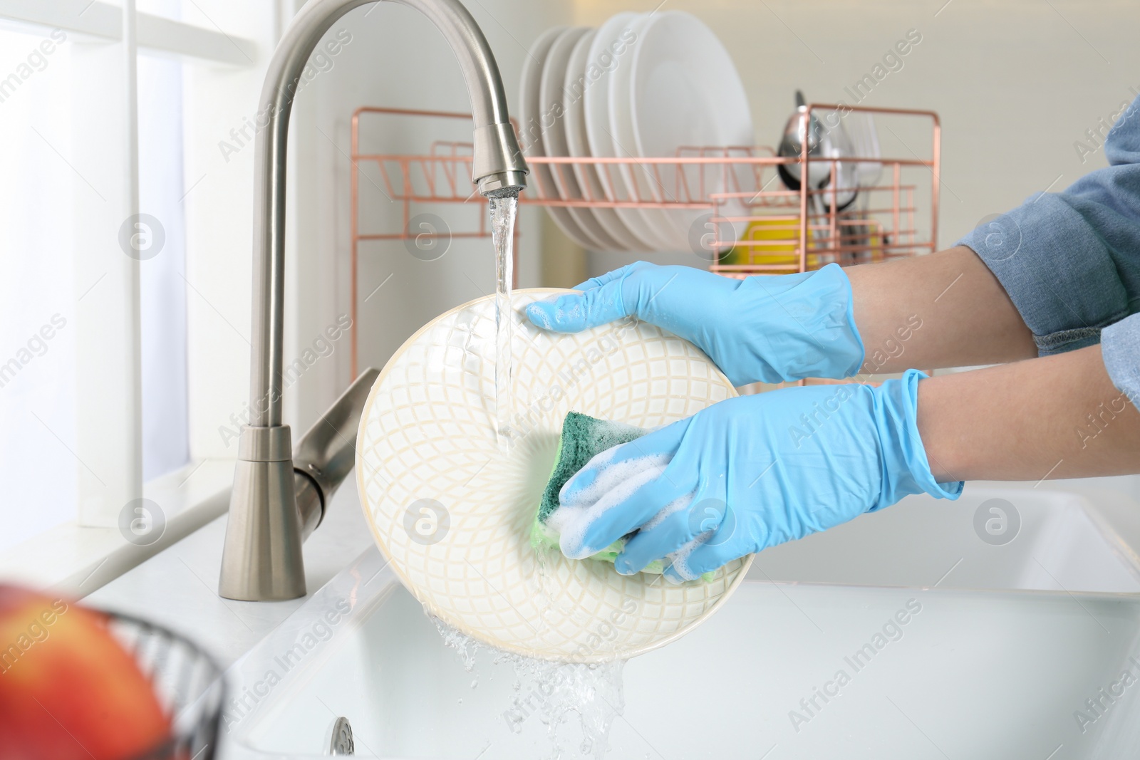 Photo of Woman washing plate in modern kitchen, closeup