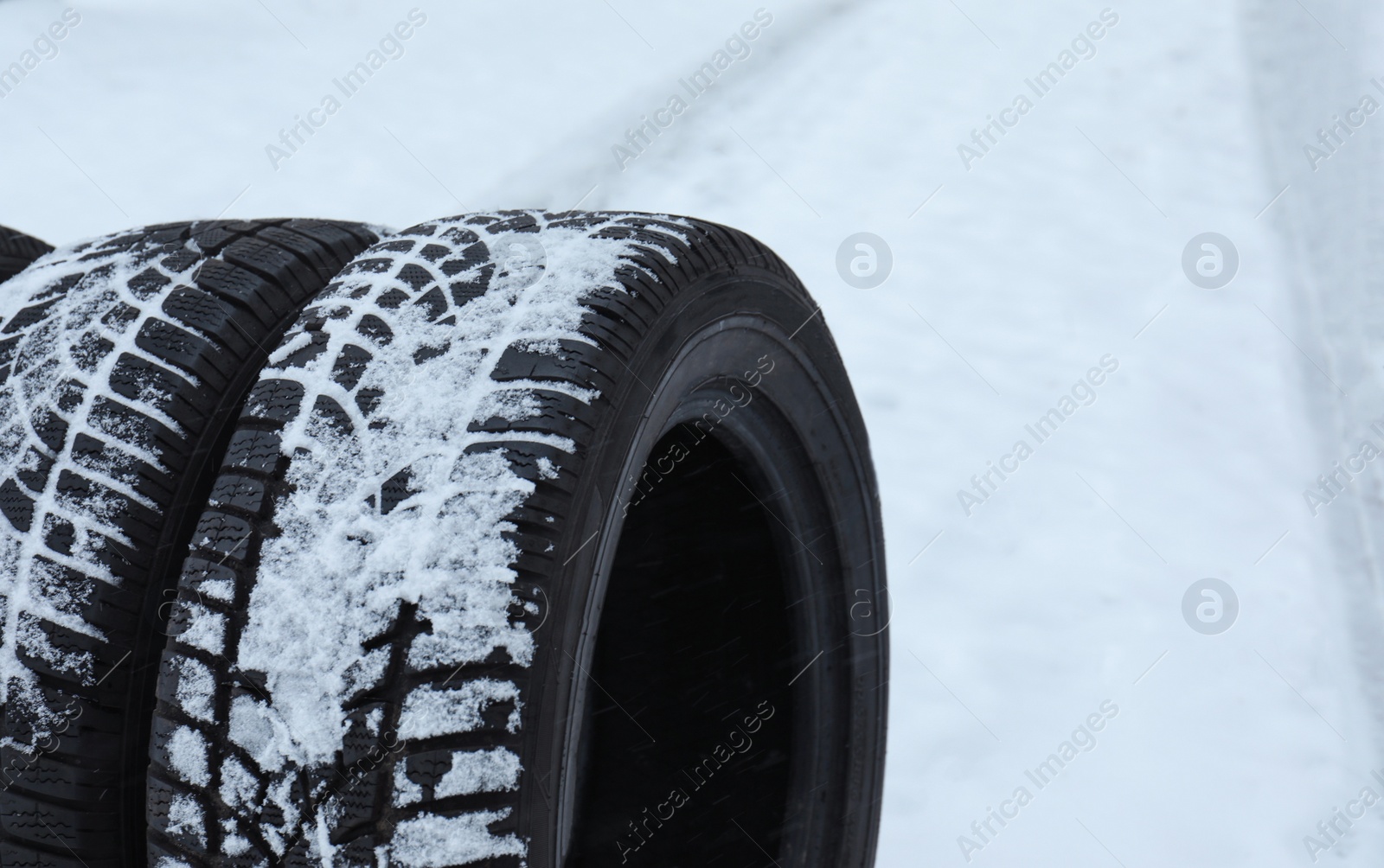 Photo of New winter tires on fresh snow, closeup. Space for text