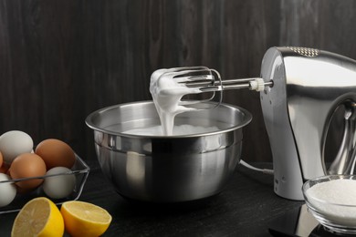 Bowl with whipped cream, hand mixer and ingredients on black table