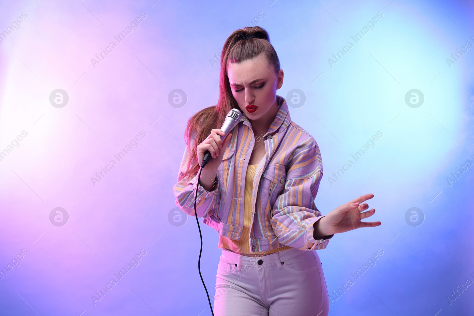 Photo of Emotional woman with microphone singing in color lights