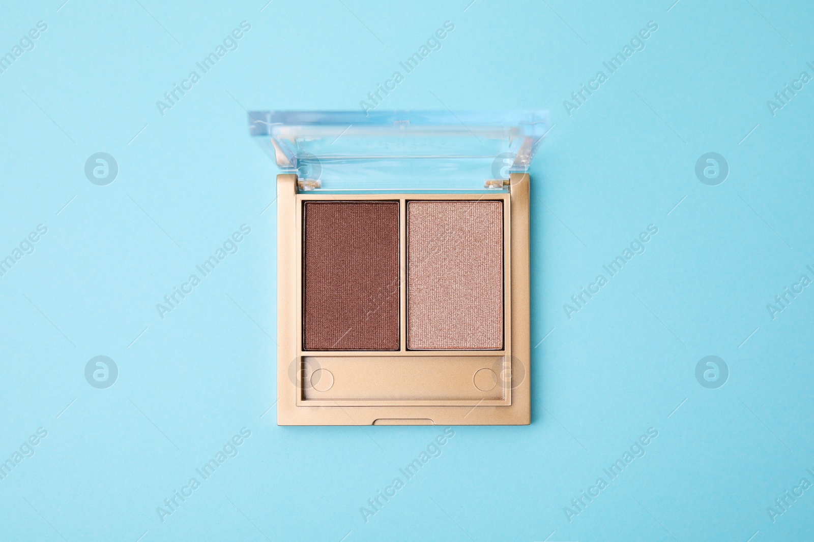Photo of Beautiful eye shadow palette on light blue background, top view