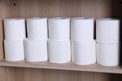 Photo of Stacked toilet paper rolls on wooden shelf