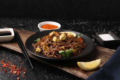 Photo of Stir-fry. Tasty noodles with vegetables and meat served on dark textured table