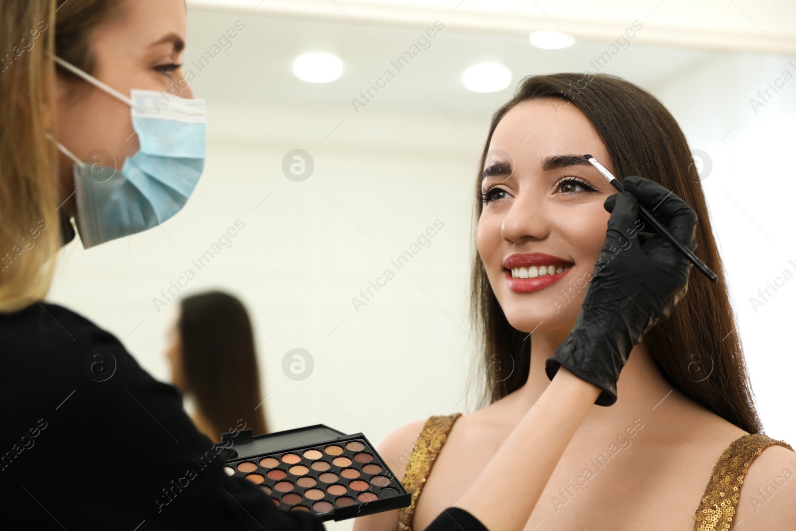 Photo of Professional makeup artist working with client in salon. Beauty services during Coronavirus quarantine