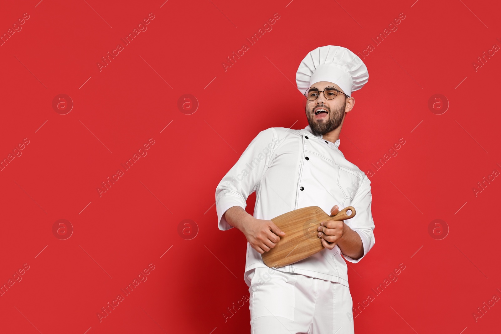 Photo of Professional chef with serving board having fun on red background. Space for text