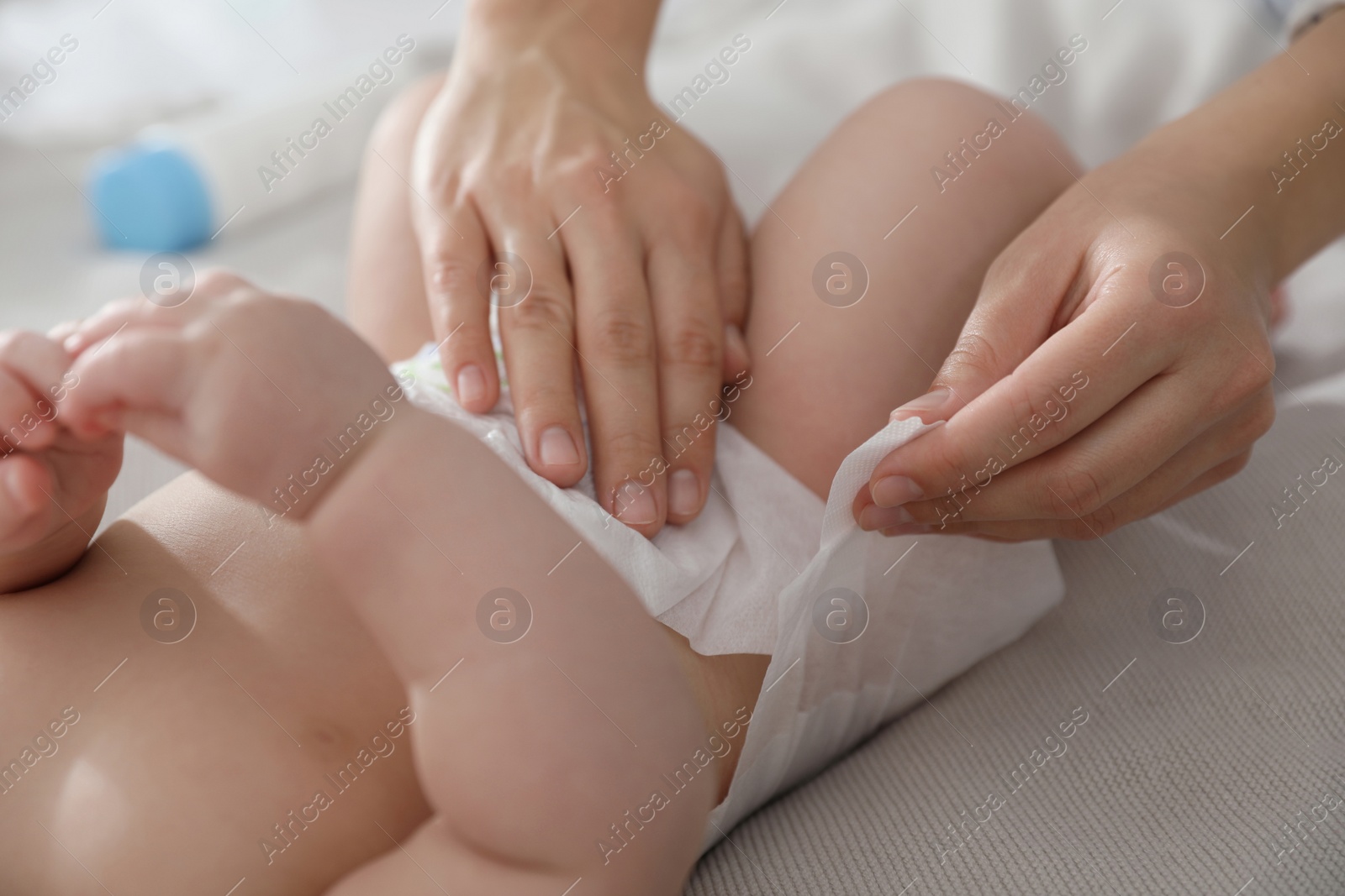 Photo of Mother changing her baby's diaper on bed, closeup